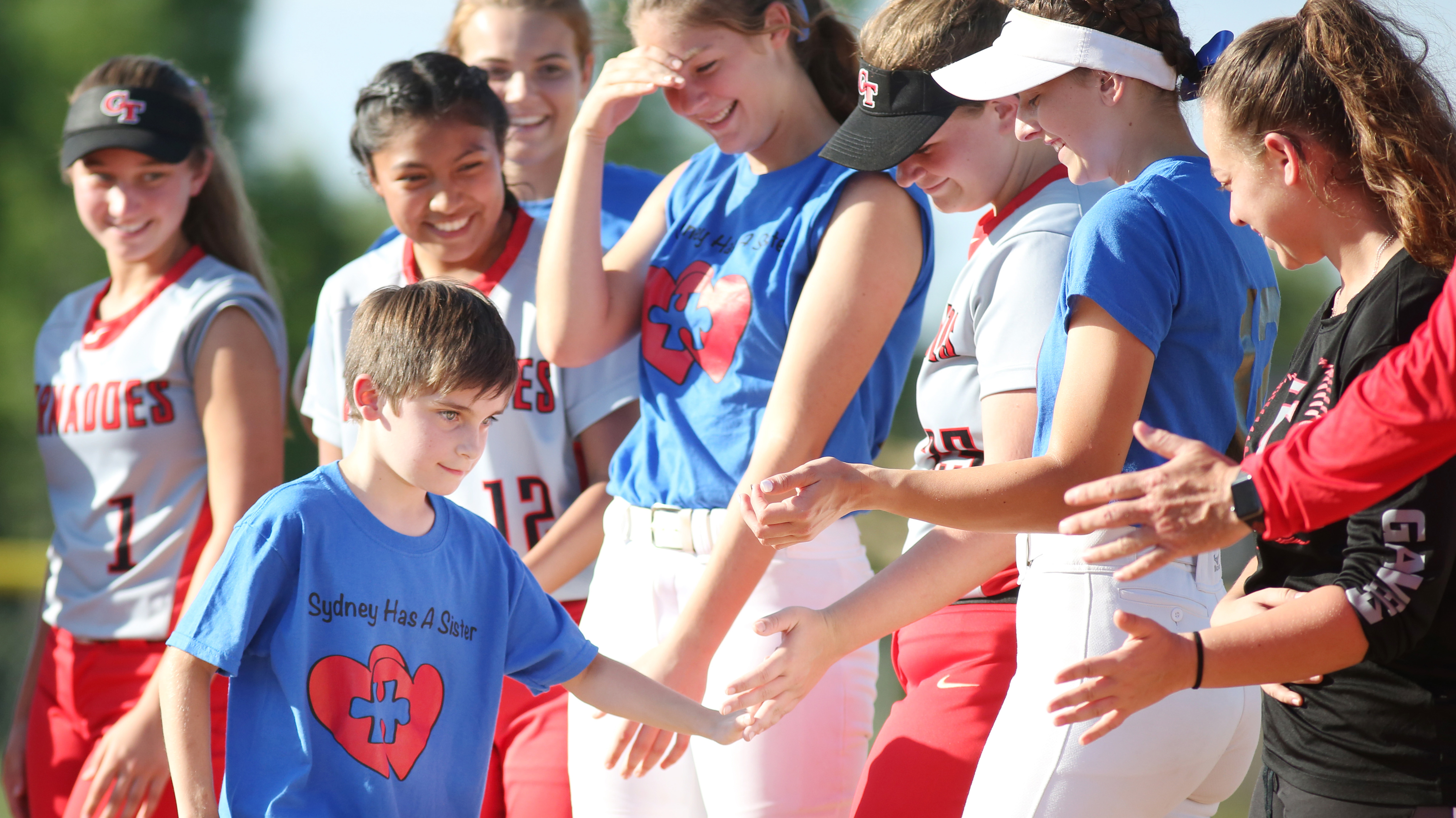 Carson Lord, 9, receives a bunch of high-fives from Sunlake and Clearwater softball players moments after Lord threw out the first pitch. (SCOTT PURKS | Special to the Times) Carson Lord, 9, receives a bunch of high-fives from Sunlake and Clearwater softball players moments after Lord threw out the first pitch. (SCOTT PURKS | Special to the Times)