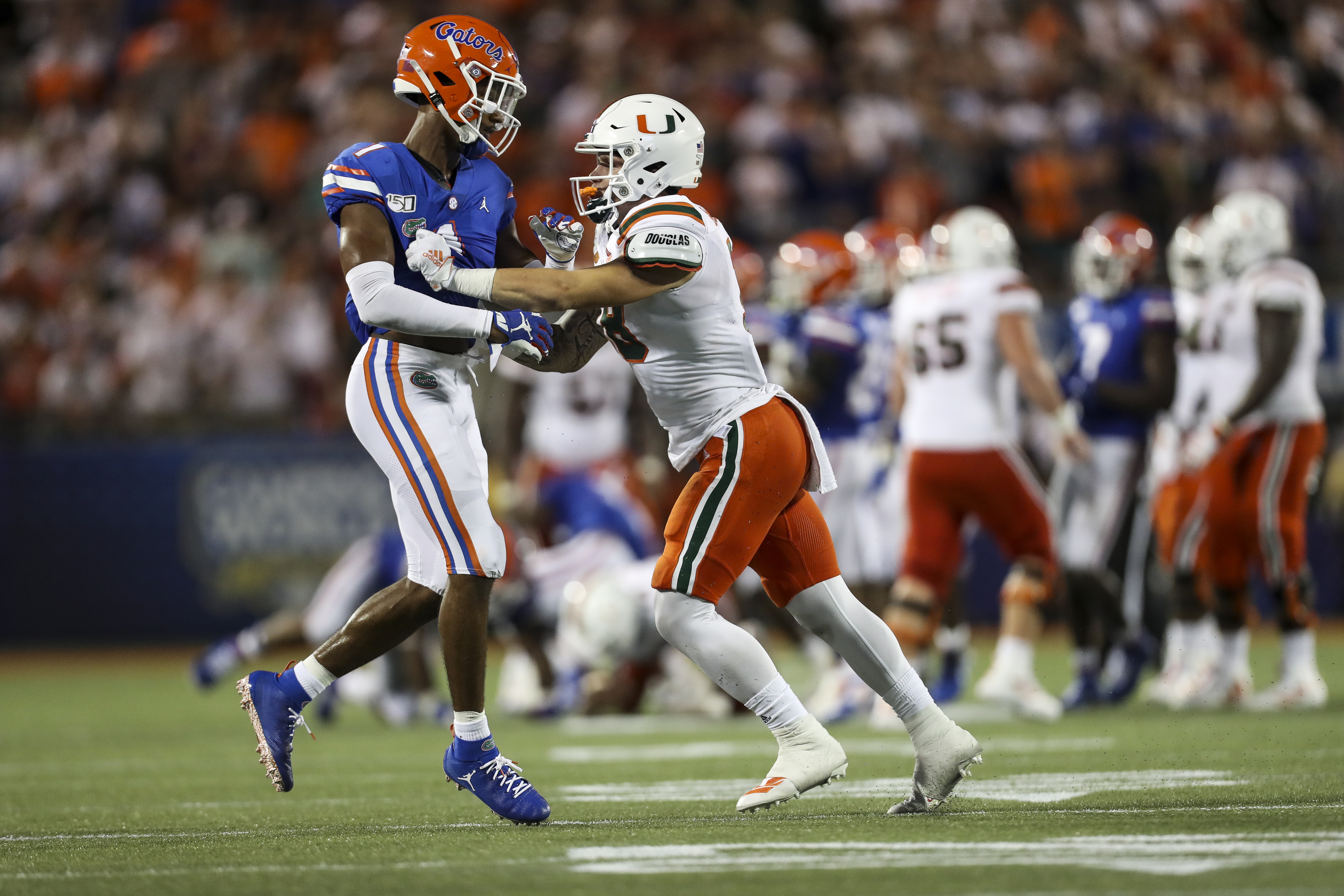 Miami quarterback Tate Martell (18) shoves Gators defensive back CJ Henderson (1) during the fourth quarter of the season opener at Camping World Stadium. MONICA HERNDON | Tampa Bay Times Miami quarterback Tate Martell (18) shoves Gators defensive back CJ Henderson (1) during the fourth quarter of the season opener at Camping World Stadium. MONICA HERNDON | Tampa Bay Times